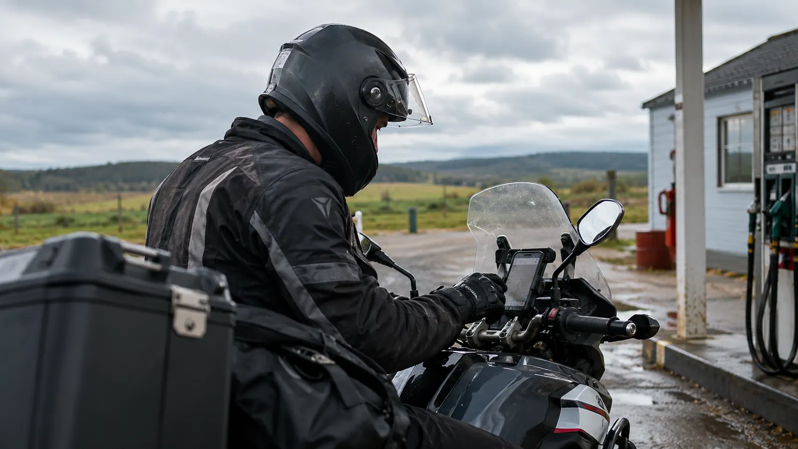 Rider checking a phone on the handlebar mount at a fuel stop