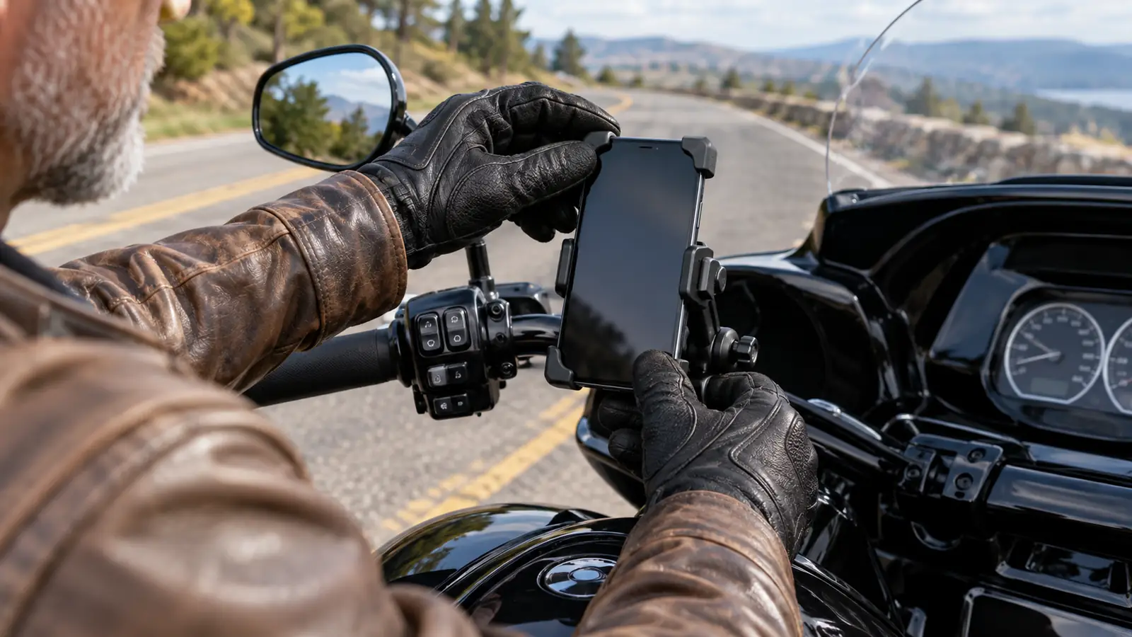 Rider's gloved hand fitting a phone into the handlebar mount on a touring motorcycle